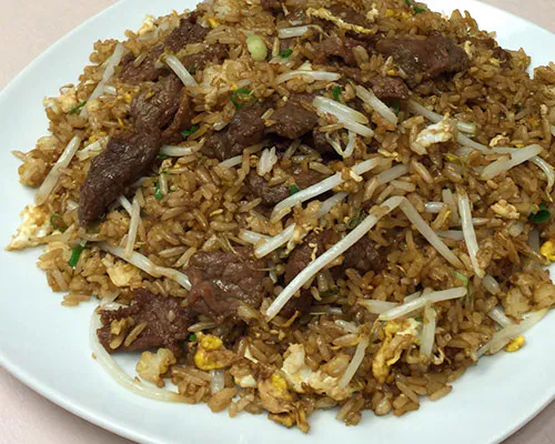Beef fried rice with bean sprouts, egg, and scallions on a white plate